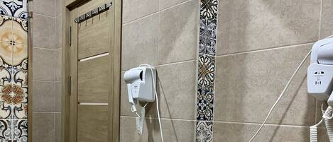 Un baño con lavabo, espejo y toallero. Hay artículos de aseo personal y un kit de afeitado en la encimera.