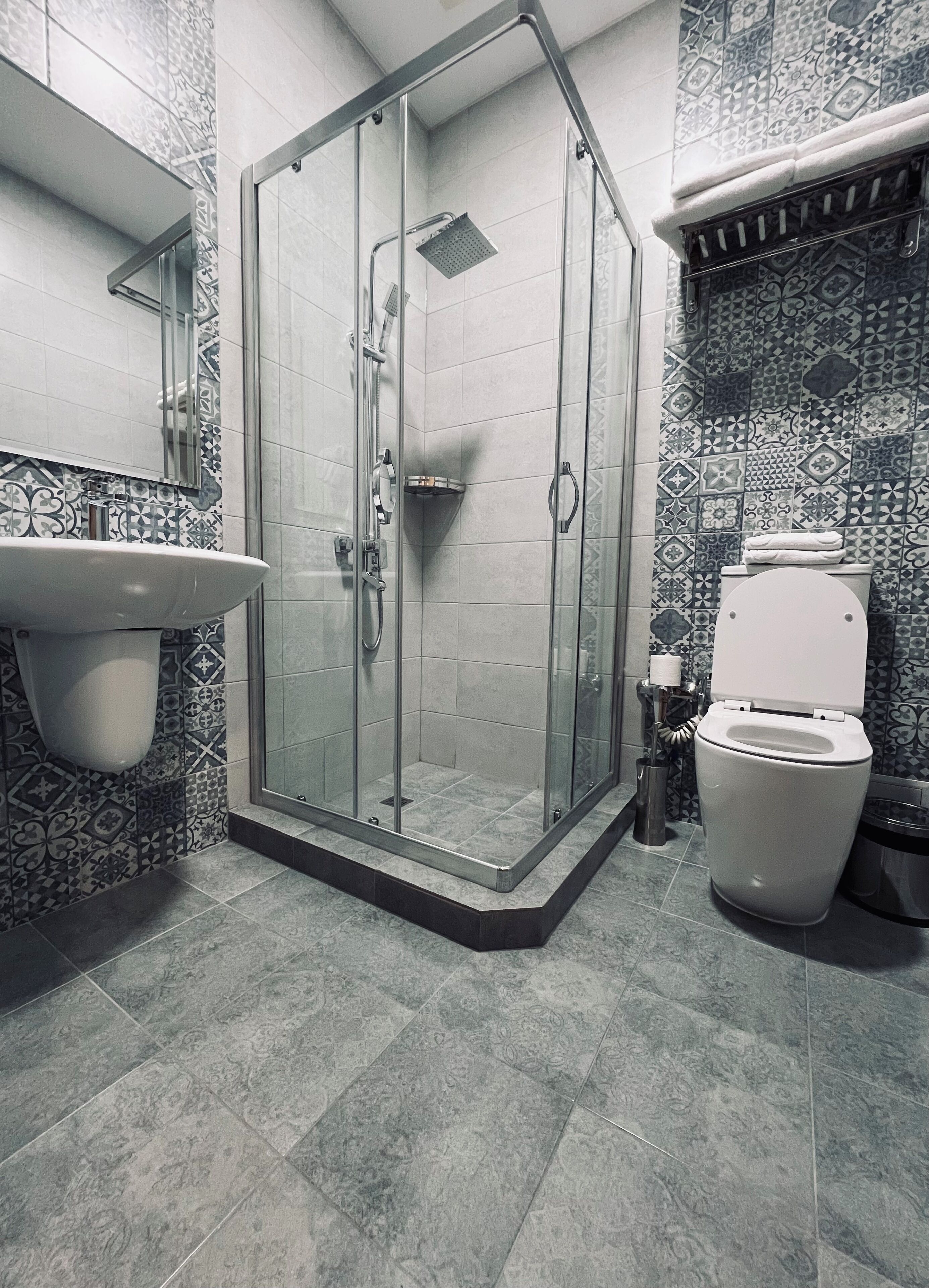 A bathroom with a glass shower enclosure, a sink with a mirror, and a toilet.