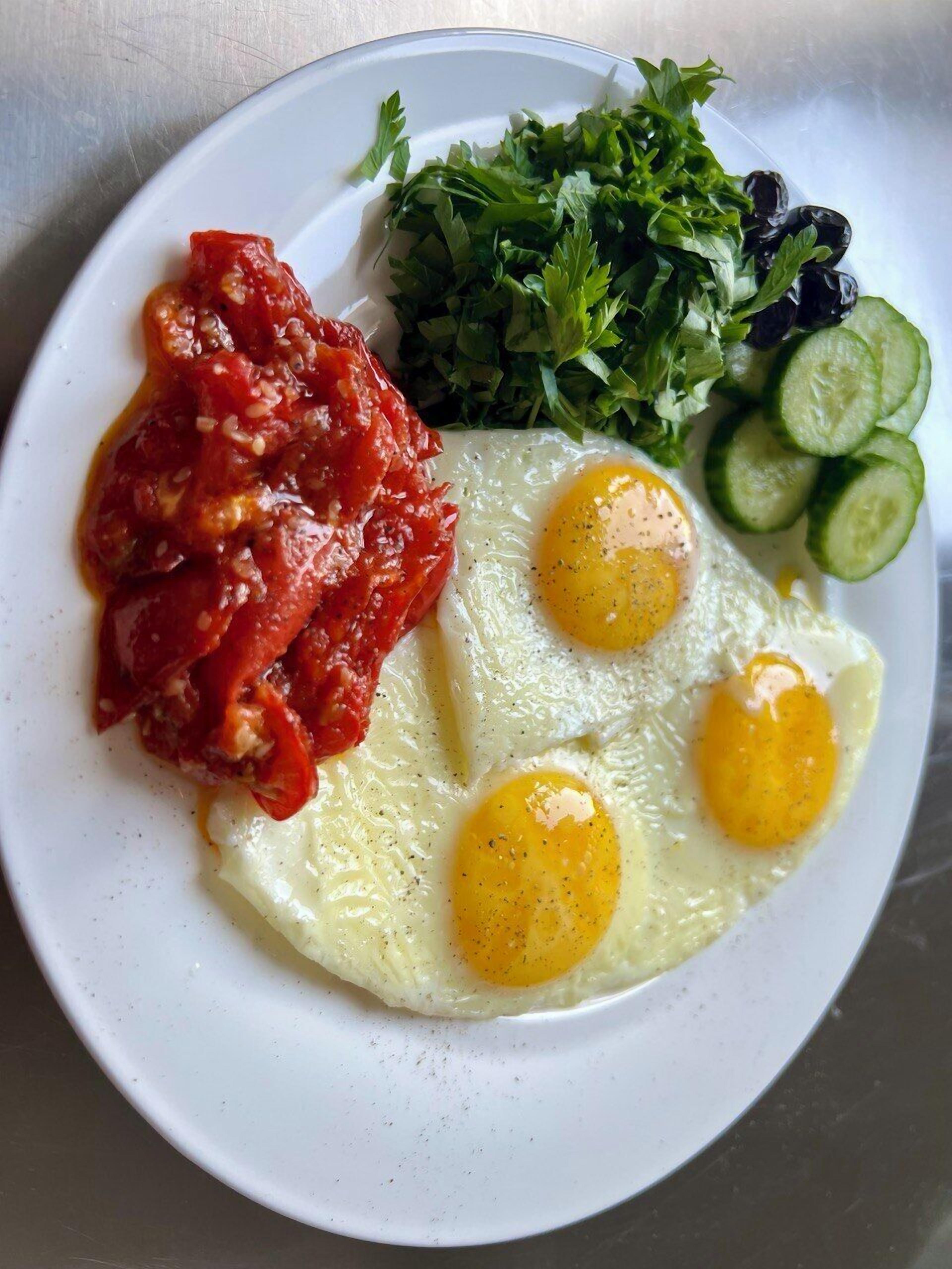 A plate with eggs, tomato sauce, and a side salad.