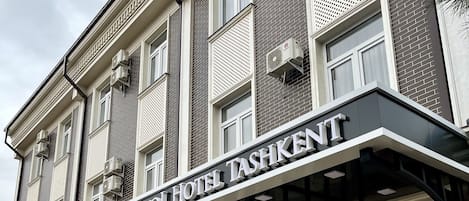 A hotel facade with a sign reading "BRISTOL HOTEL TASHKENT" and a logo with "HB".