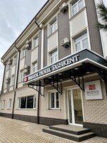 Fachada de un hotel con un letrero que dice "BRISTOL HOTEL TASHKENT" y un logotipo con "HB".