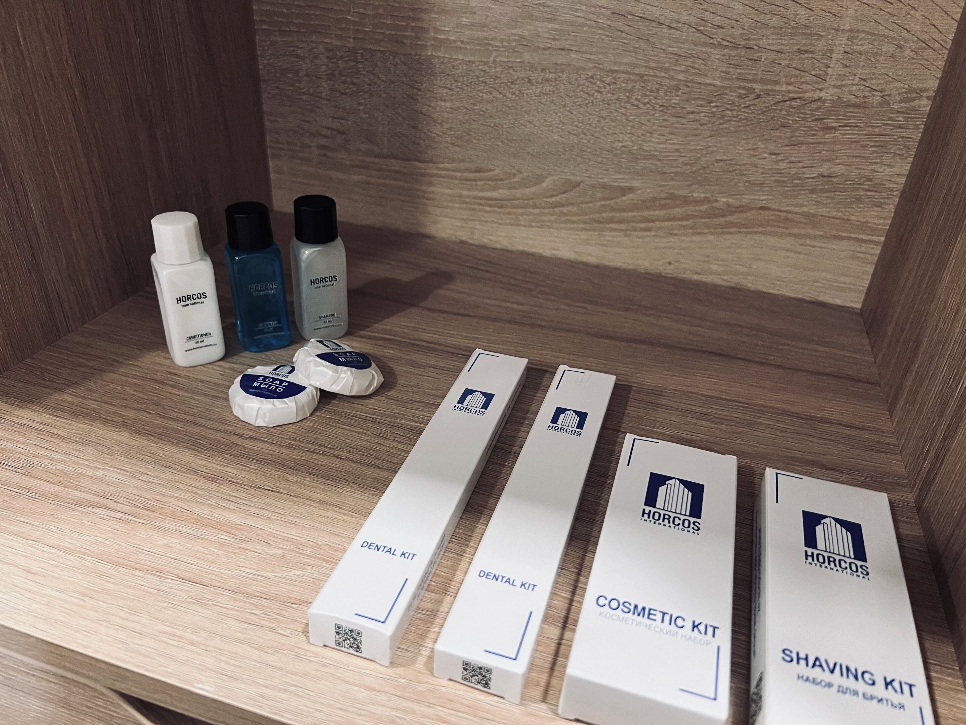 A wooden shelf with various Horcos International products including a conditioner, shampoo, and shaving kit.