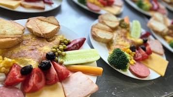 En buffet med forskellige spiser, herunder kød, oste og grøntsager.