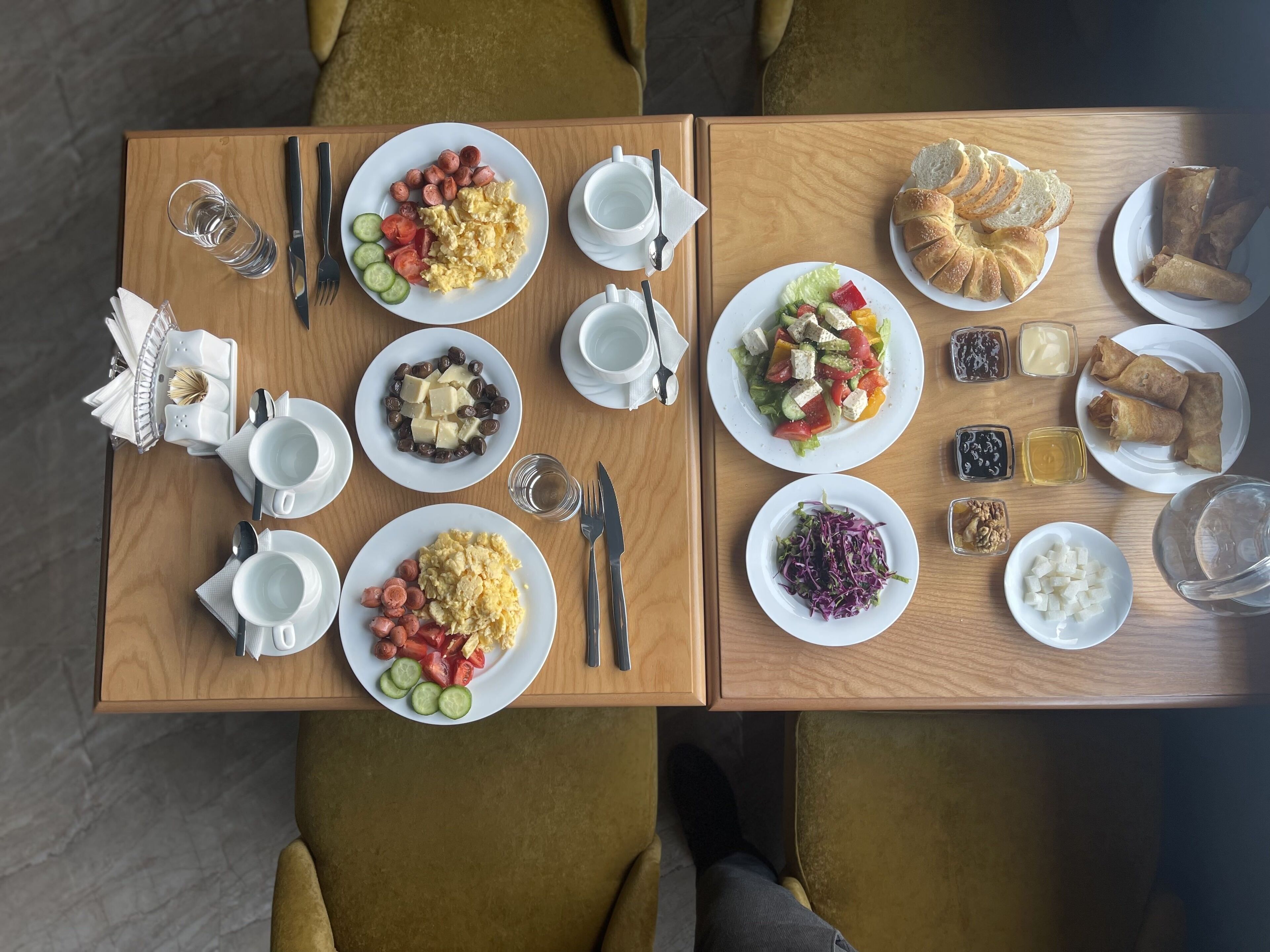 A dining table with plates of food, utensils, and condiments.
