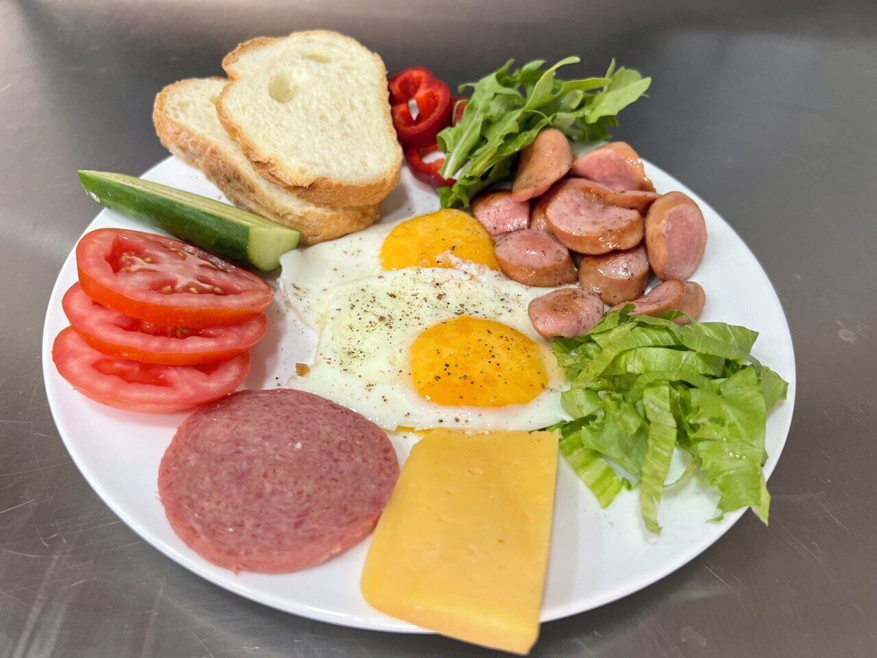 A plate with a variety of breakfast items including eggs, sausage, cheese, and vegetables.