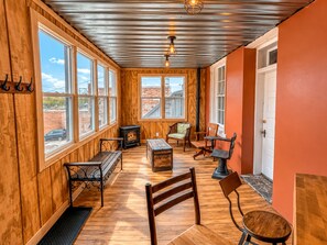 A cozy room with wooden walls, a fireplace, and a large window overlooking a brick building.