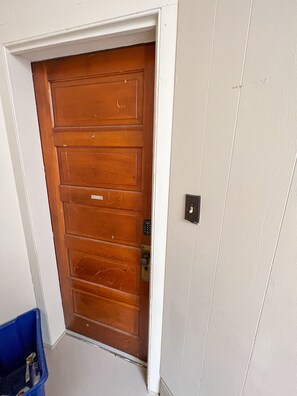 A wooden door with a keypad lock, a blue bin, and a white wall. - Close to Local Opera House - On the main drag (Mineral Point)