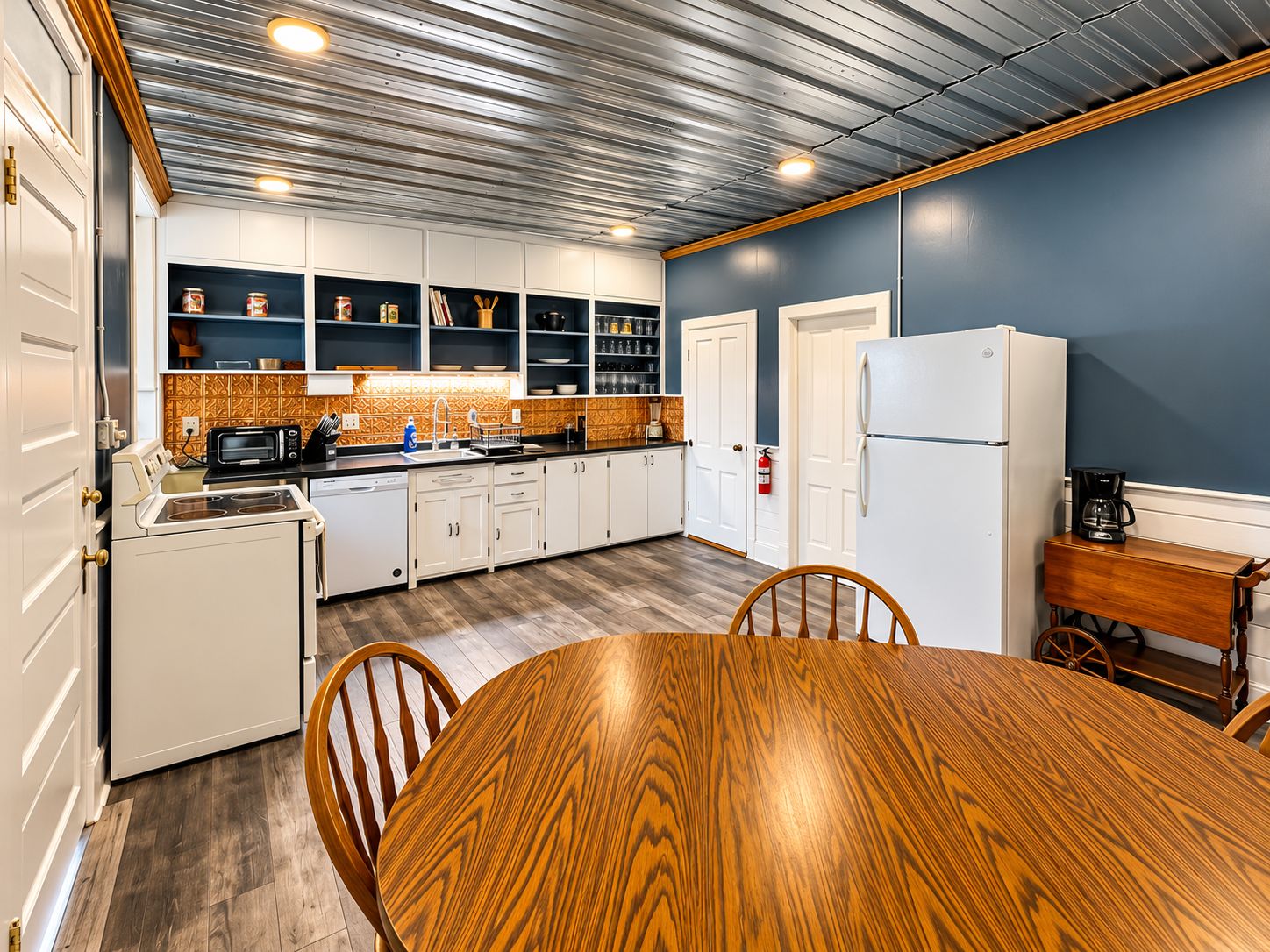 A kitchen with white cabinets, a wooden dining table, and a blue accent wall.