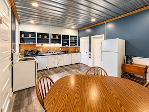 A kitchen with white cabinets, a wooden dining table, and a blue accent wall.
