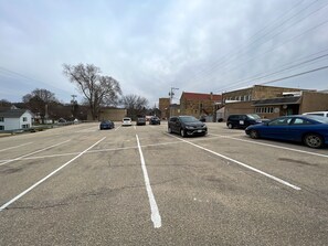 Un parking avec plusieurs voitures garées, des bâtiments en arrière-plan et un ciel dégagé.