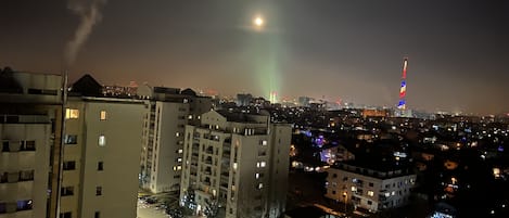 A nighttime cityscape with a prominent building featuring a tall tower with colorful lights.