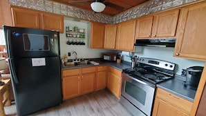 A kitchen with wooden cabinets, a black refrigerator, a stainless steel stove, and a microwave. - Hocking Hills secluded Mayapple Cabin - 8 miles from Cantwell Cliffs! ~Hot Tub~ (Rockbridge)