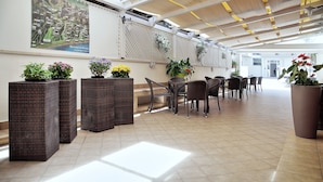 A spacious indoor area with wicker furniture, potted plants, and a large map on the wall.