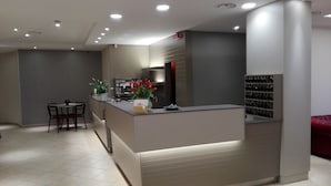 A modern reception area with a counter, seating, and a coffee machine.