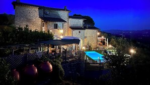 A stone house with a swimming pool, outdoor seating, and a view of the surrounding landscape. - Villa Borgo Soale in Tuscany—Reggello. Private pool and Wi-Fi (Toscana)