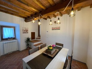 A dining area with a wooden table, chairs, and hanging light fixtures.
