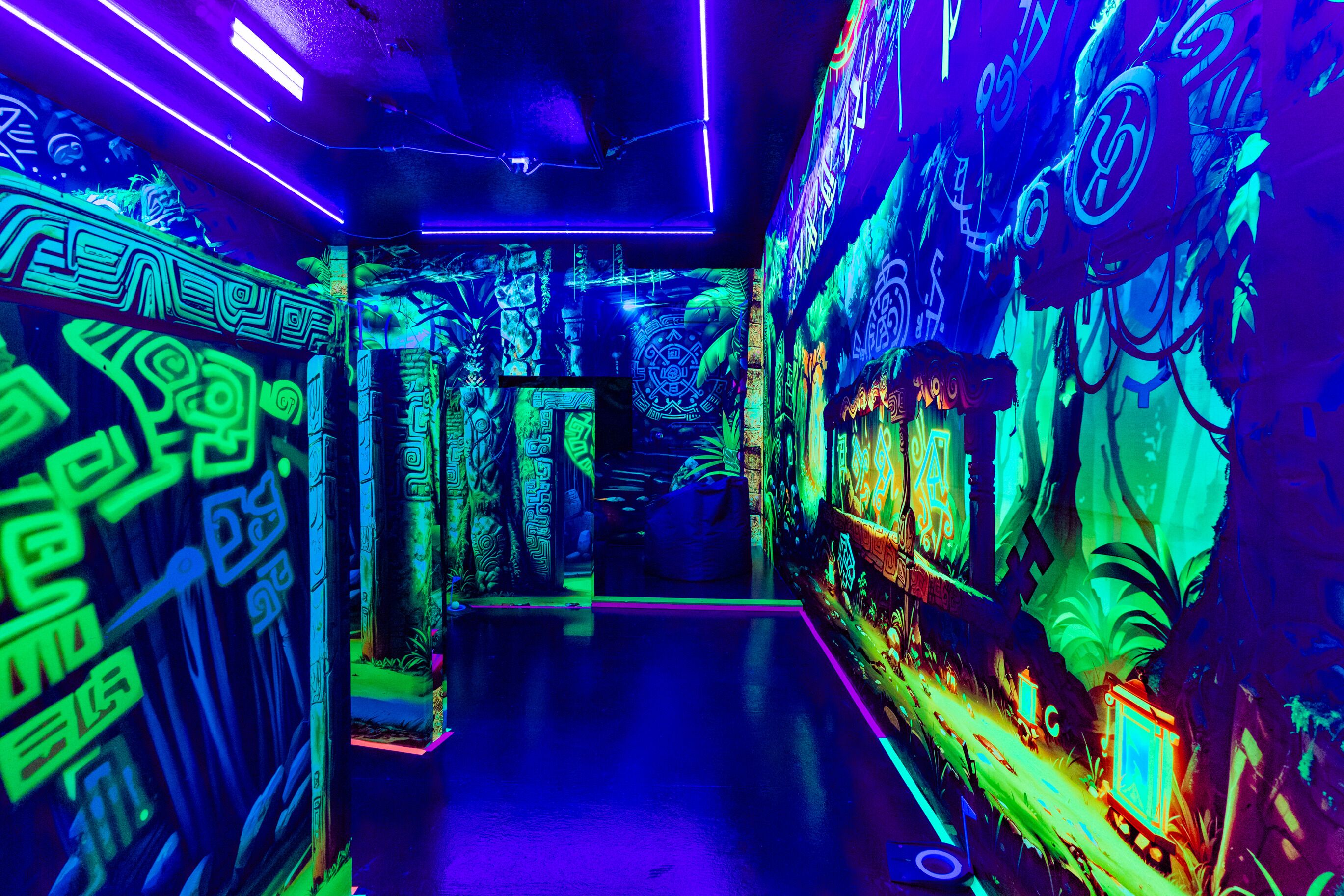 Een neonverlichte hal met ingewikkelde wanddecoraties en een bankje.