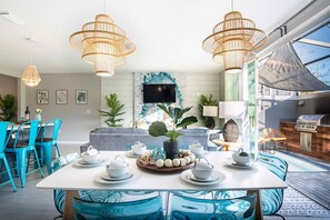 A modern dining area with a white table set for four, surrounded by blue chairs.