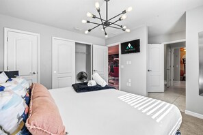A bedroom with a bed, a ceiling fan, and a TV mounted on the wall.