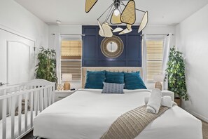 A bedroom with a bed, a crib, a hanging light fixture, and a wall-mounted mirror. - Sleeps 21 / Disney & Universal Retreat w/ Game Room + Pool, Spa (Kissimmee)