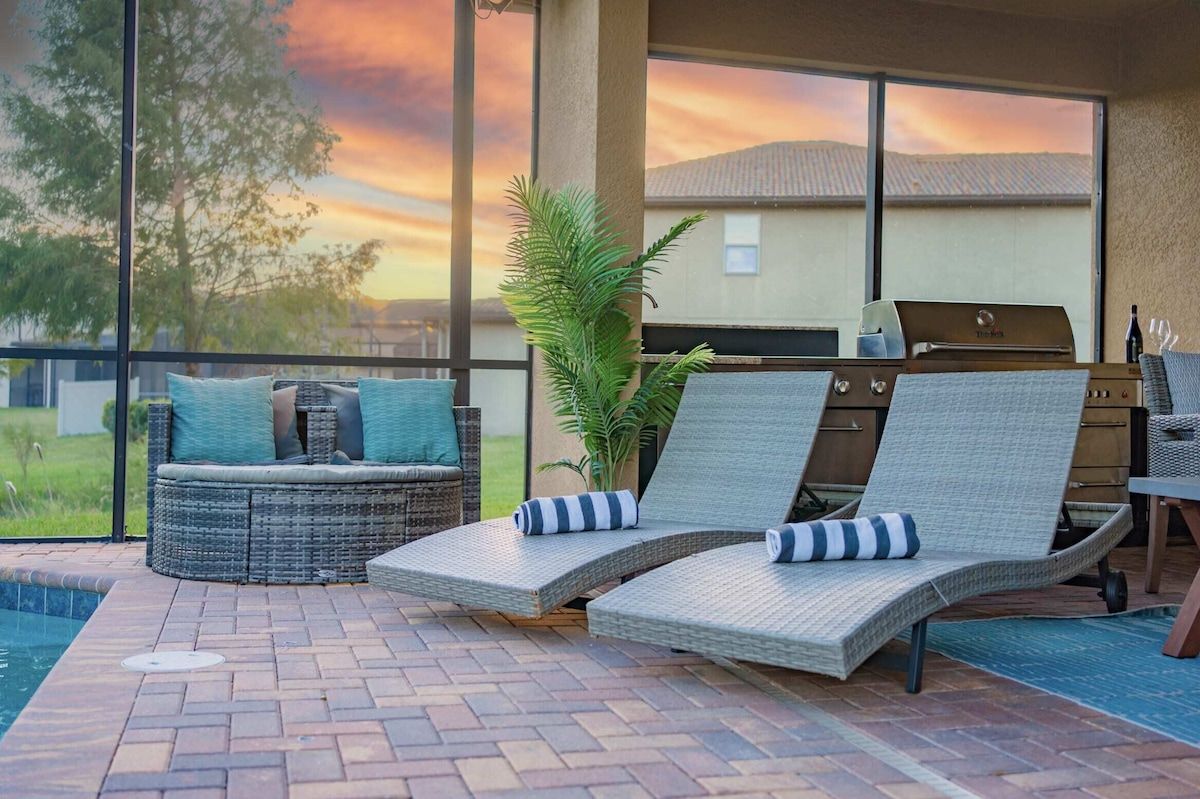 A patio with two lounge chairs, a small pool, and a grill area.