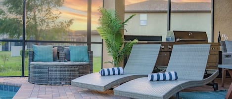 A patio with two lounge chairs, a small pool, and a grill area.