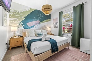 A modern bedroom with a large bed, a wall mural, a chandelier, and a window with curtains. - Sleeps 21 / Disney & Universal Retreat w/ Game Room + Pool, Spa (Kissimmee)