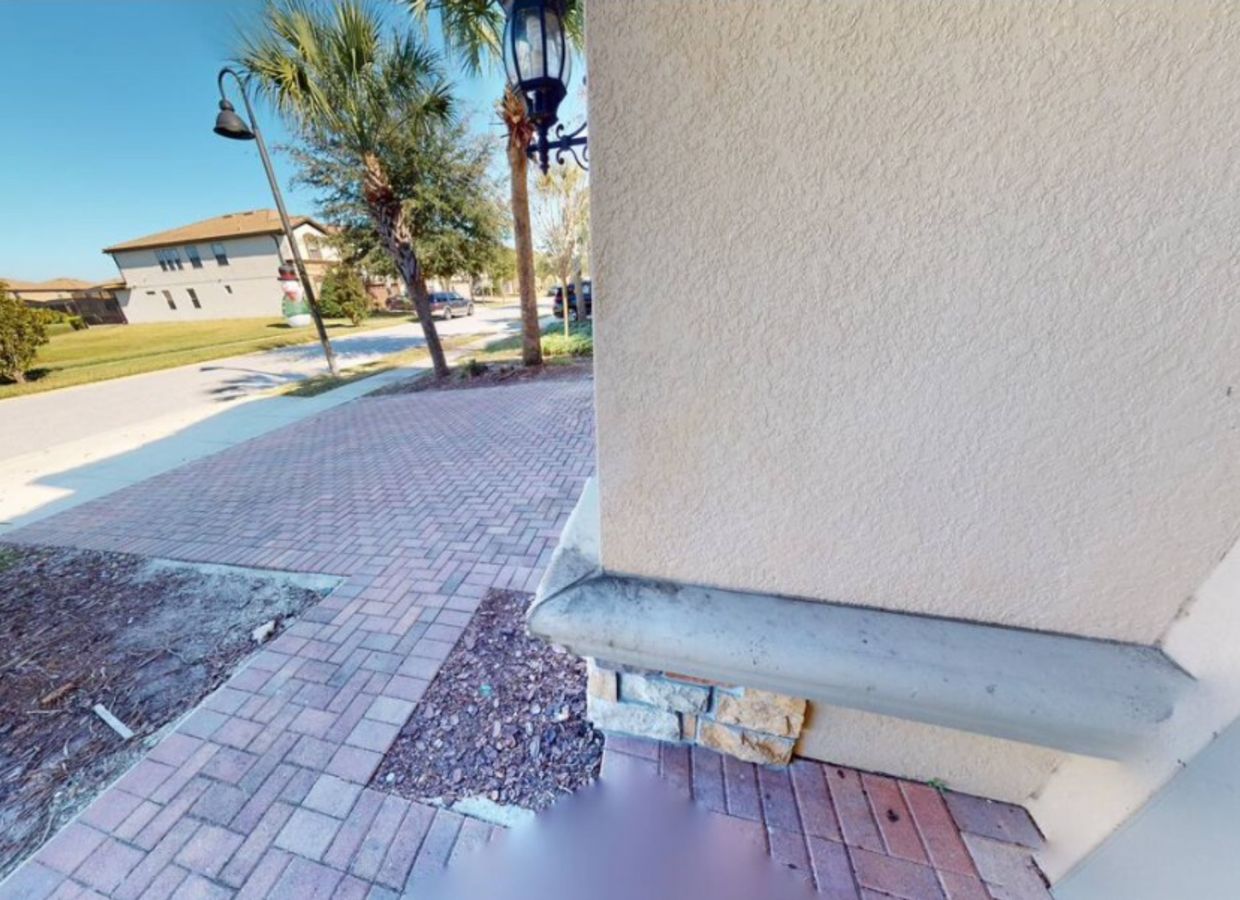 Un trottoir dallé bordé d’une bordure, avec un palmier et un lampadaire.