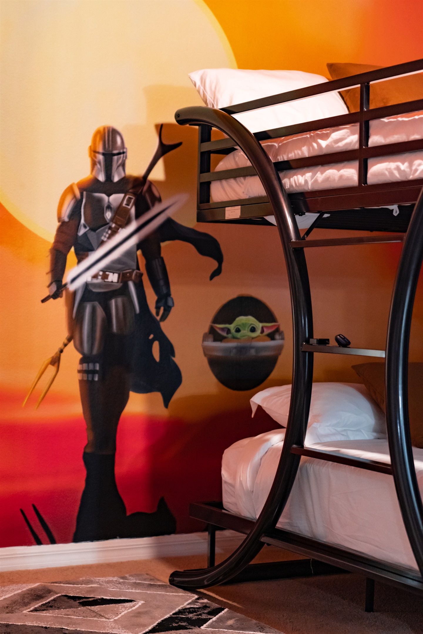 Ein Etagenbett mit Wandbild zum Thema Star Wars, einem Star-Wars-Helm und einer Star-Wars-Figur.