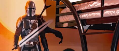 Ein Etagenbett mit Wandbild zum Thema Star Wars, einem Star-Wars-Helm und einer Star-Wars-Figur.