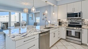 A modern kitchen with a large island, stainless steel appliances, and pendant lighting. - Stunning Gulf views, 2BR Corner Unit, at Tops'l resort! (Miramar Beach)