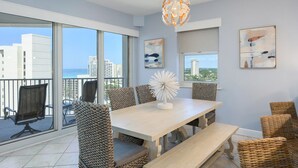 A modern dining area with a large table, wicker chairs, and a decorative light fixture. - Stunning Gulf views, 2BR Corner Unit, at Tops'l resort! (Miramar Beach)