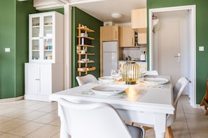 A dining area with a table set for four, a white cabinet with glass doors, and a wooden shelf unit.