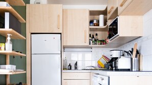 Et lille køkken med træskabe, indbygget ovn og mikrobølgeovn.