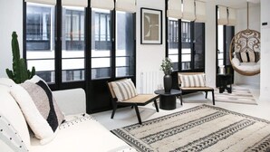 A modern living room with large windows, a hanging chair, and a patterned rug.