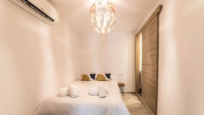 Una habitación de hotel con una cama, una puerta de madera y una pequeña mesa con una silla.