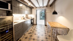 Una cocina moderna con armarios grises, una mesa de comedor de madera y una silla transparente.