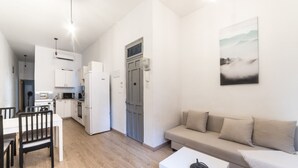 En kompakt bolig med tekøkken, spiseplads og opholdsområde med sofa og sofabord.