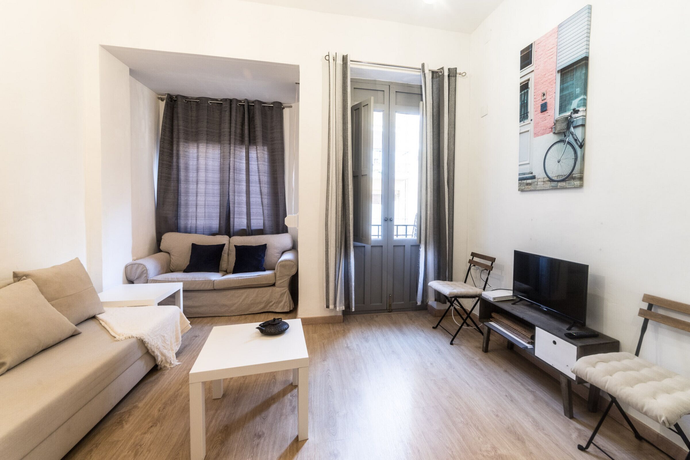 A living room with a sofa, a coffee table, a TV, and a painting on the wall.