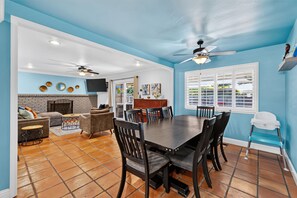A dining area with a large table and chairs, a fireplace, and a television mounted on the wall. - Oasis Pool, Outdoor Kitchen and Grill, Arcade Room, Movie Room, Sleep up to 13 (Fresno)