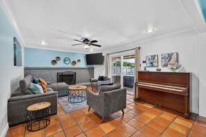 Un salon avec une cheminée, un piano et un téléviseur.