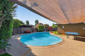 A swimming pool with a surrounding deck, a covered seating area, and a ping pong table. - Oasis Pool, Outdoor Kitchen and Grill, Arcade Room, Movie Room, Sleep up to 13 (Fresno)