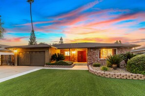 A two-story house with a well-maintained lawn, a brick exterior, and a garage. - Oasis Pool, Outdoor Kitchen and Grill, Arcade Room, Movie Room, Sleep up to 13 (Fresno)