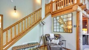 A staircase with wooden railings, a leather armchair with a throw pillow, a bench, and a floor lamp. - Luxe Cabin in the Woods: Walk to Lake! (Gaston)
