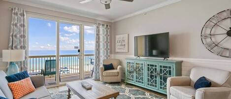 A living room with a balcony, a television, and a decorative clock on the wall.