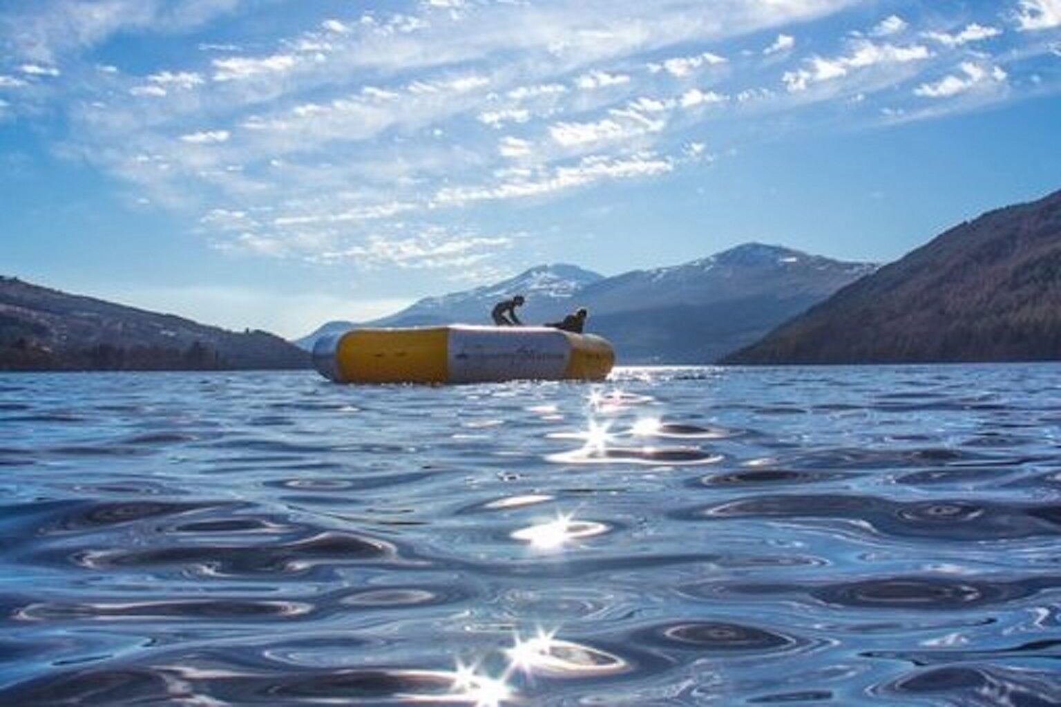 A capsule floating on water with mountains in the background.