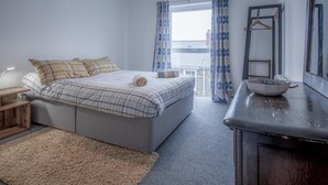 A bedroom with a bed, bedside table, and a dresser.