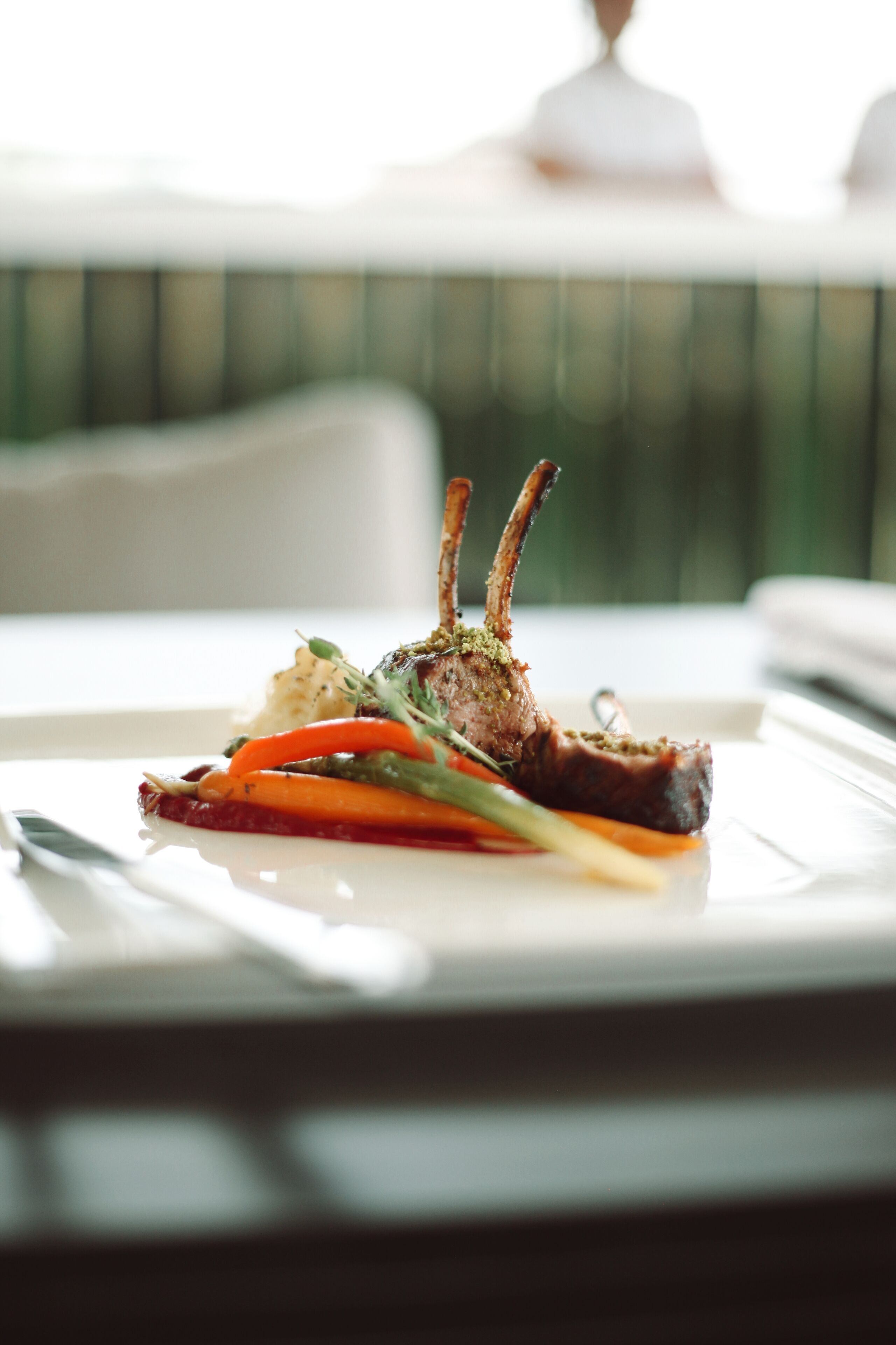 Une table à manger avec une assiette de nourriture, comprenant un jarret d’agneau et des légumes.