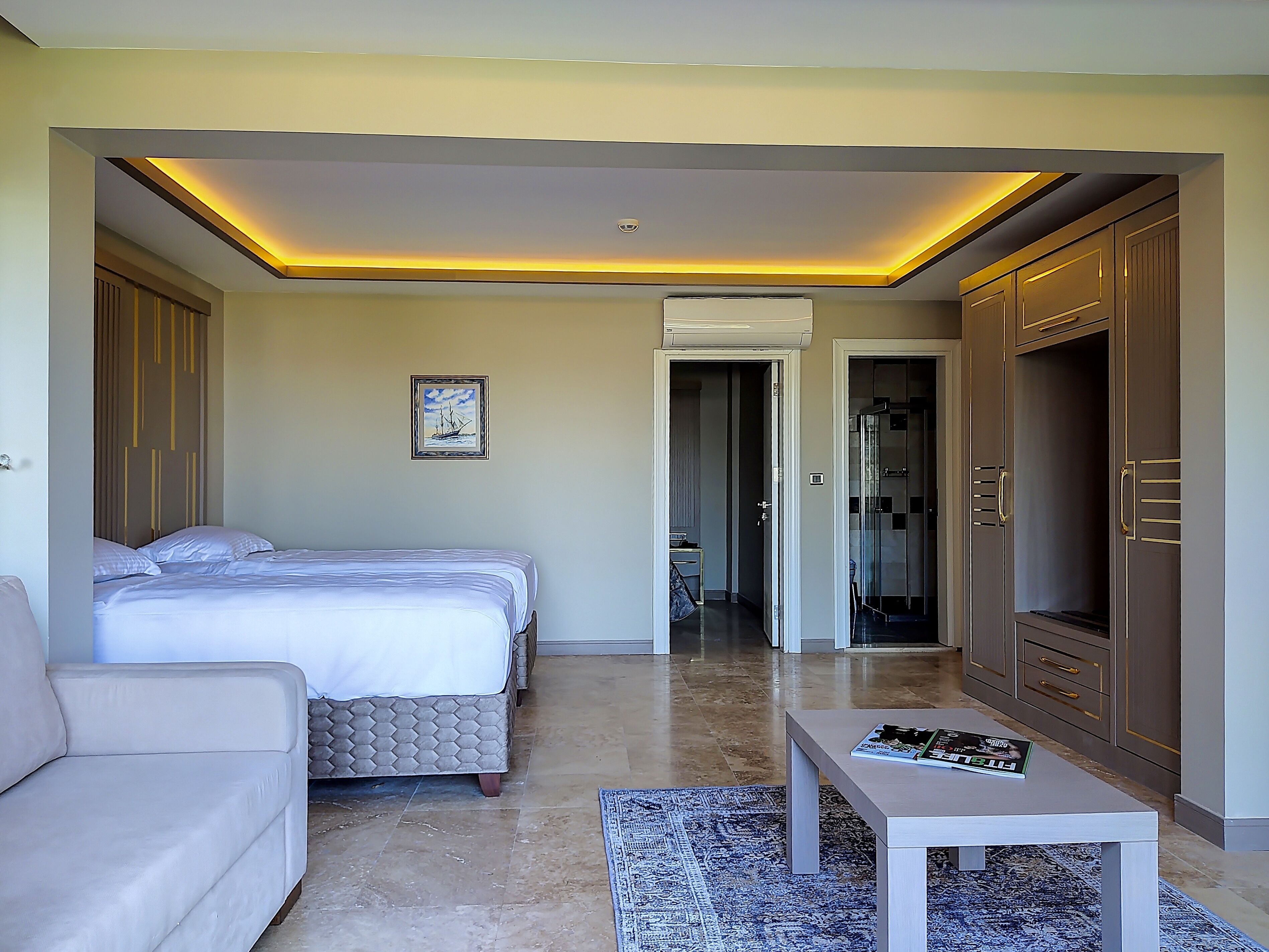 A modern hotel room with a bed, a sofa, a small table, and a wardrobe.