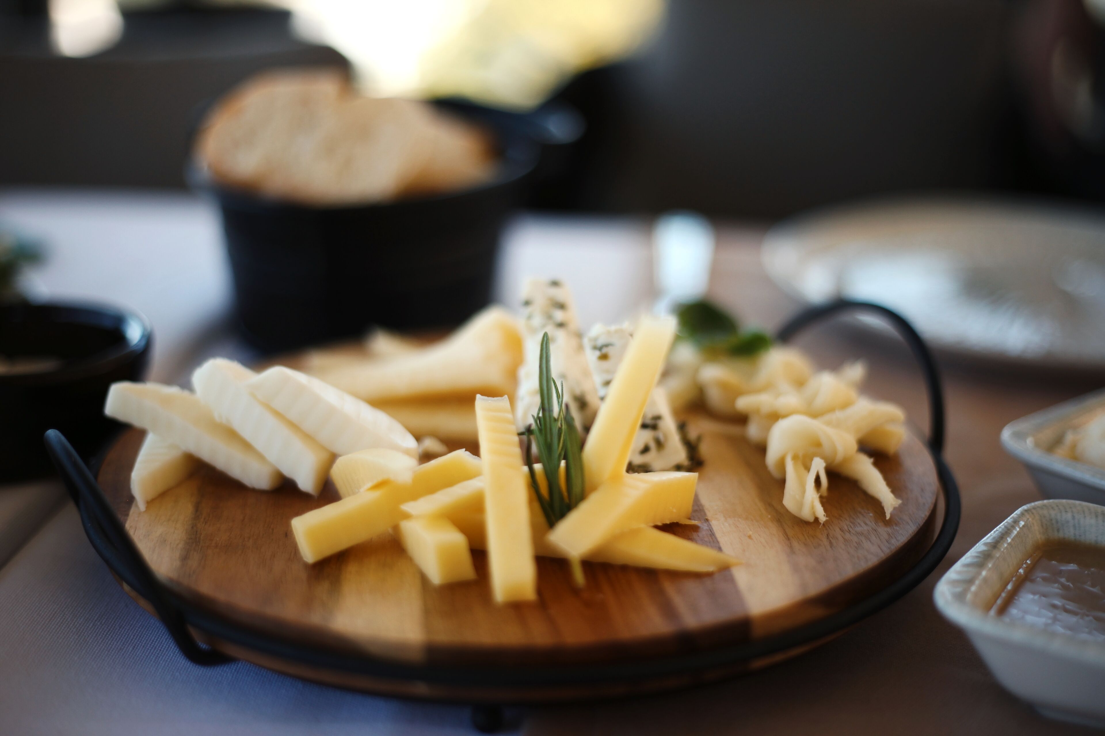 A wooden board with cheese and herbs on a table.